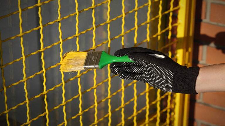 Yellow steel security mesh gate with a gloved hand