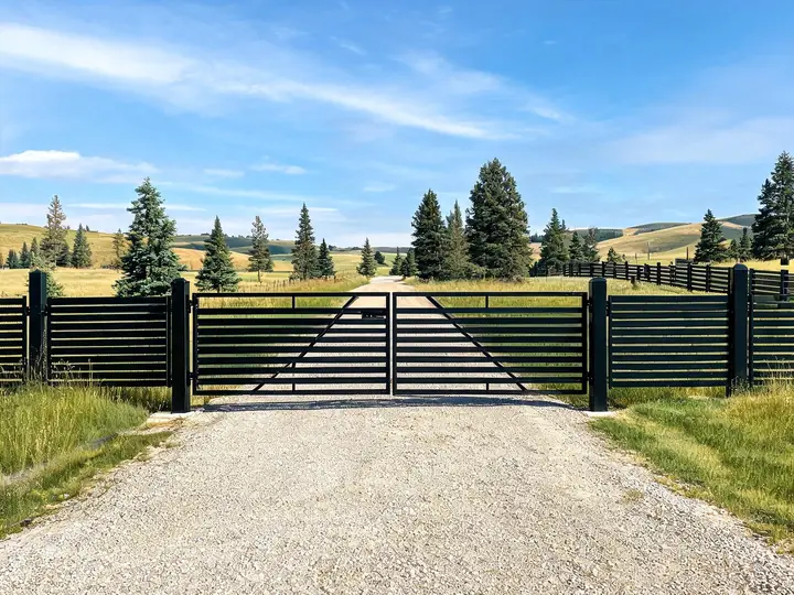 Custom welded black steel driveway gate and fence panels on a rural property