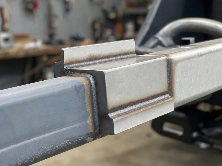 Close-up of a welded reinforcement plate on a steel gooseneck trailer coupler and tongue