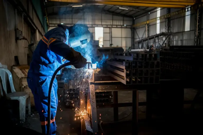 Welder welding steel on a shop table