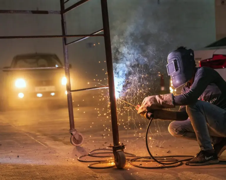 Welder working on a steel post at night with sparks