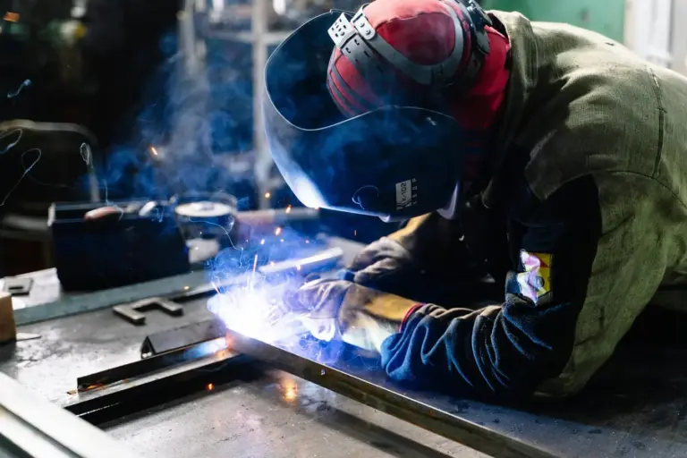 Welder in a red helmet MIG welding a steel frame