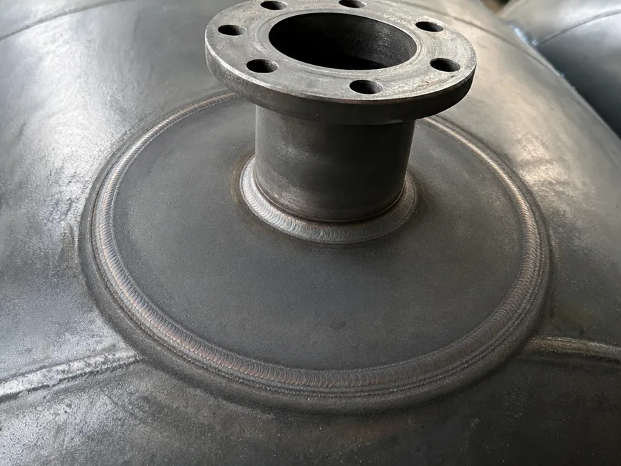 Close-up of a flanged nozzle welded onto a steel pressure vessel shell with a reinforcing pad