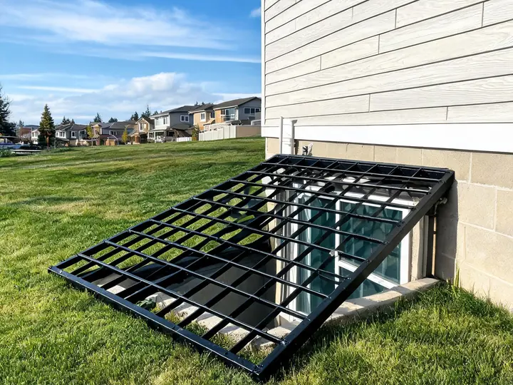Black welded steel grate cover over a basement egress window well