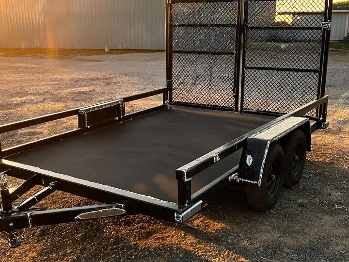 Black steel flatdeck trailer with welded frame and mesh ramp gate