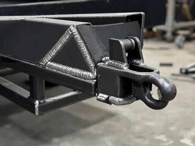 Steel trailer tongue with a pintle eye coupler and welded gusset reinforcement